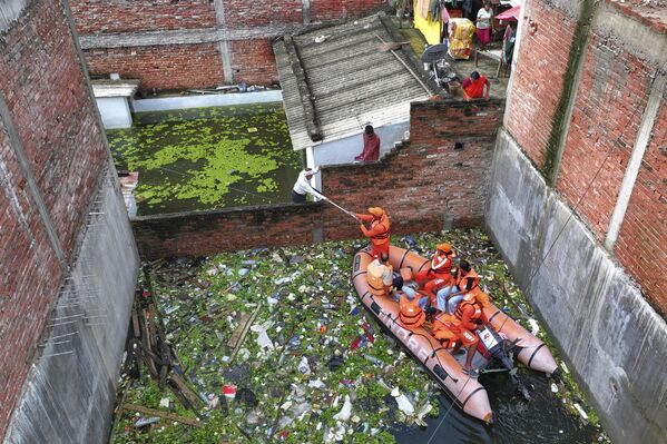 أعضاء من فرقة الكوارث الوطنية يوزعون الإمدادات الغذائية على السكان العالقين في منطقة مغمورة بالمياه بعد هطول أمطار موسمية غزيرة على ضفاف نهر الغانغ، في براياغراج، الهند. - سبوتنيك عربي
