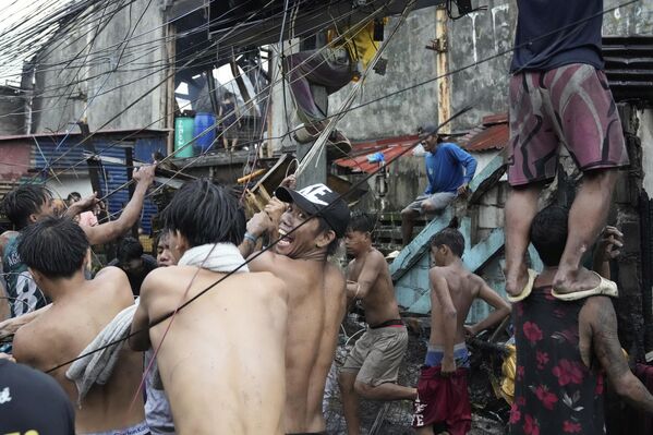 السكان يسحبون الأسلاك الكهربائية بعد أن اندلع حريق في حي فقير في مانيلا، الفلبين. - سبوتنيك عربي