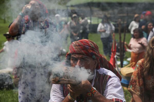 قائدٌ من السكان الأصليين يُرشد الناس بالبخور وموسيقى الطبول خلال احتفال محلي للاحتفال بالانقلاب الصيفي في موقع سان أندريس الاحتفالي، 22 يونيو/حزيران 2025، في لا ليبرتاد، السلفادور. - سبوتنيك عربي