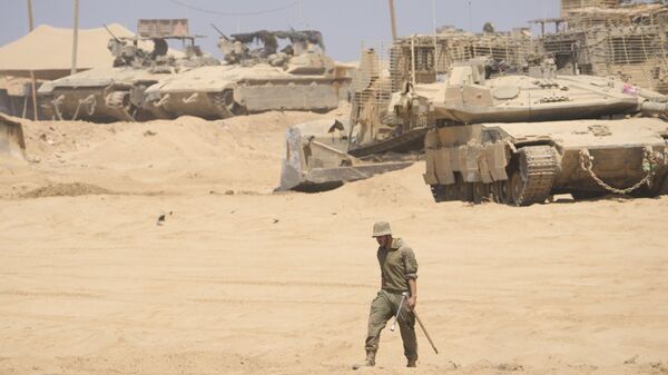 جندي إسرائيلي يعمل على دبابة في منطقة  على الحدود مع قطاع غزة - سبوتنيك عربي