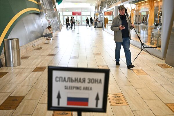 صحفي يسير حاملا بعض المعدات الصحفية في صالة مركز الخطوط الجوية الرياضية، قبل القمة المرتقبة بين الرئيس الروسي فلاديمير بوتين والرئيس الأمريكي دونالد ترامب في ألاسكا. - سبوتنيك عربي