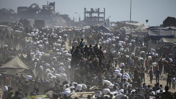 فلسطينيون يحملون أكياس الدقيق المأخوذة من قافلة مساعدات إنسانية في طريقها إلى مدينة غزة، على مشارف بيت لاهيا، شمال قطاع غزة، 1 أغسطس/ آب 2025 - سبوتنيك عربي