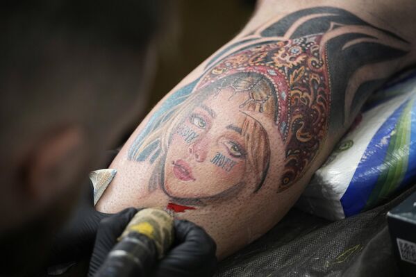 رجل يحصل على وشم لفتاة ترتدي "كوكوشنيك"، خلال مهرجان للوشم في موسكو، روسيا. - سبوتنيك عربي