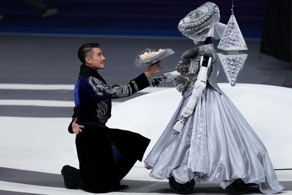 عارض الأزياء والممثل هو بينغ، يقدم باقة ورد لروبوت بشري في حفل افتتاح دورة الألعاب العالمية لـ"الروبوتات البشرية 2025" في بكين، الصين. - سبوتنيك عربي