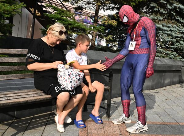شاب يرتدي زي "سبايدر مان" يمازح طفل في شارع الأدميرال فوكين في فلاديفوستوك، روسيا. - سبوتنيك عربي