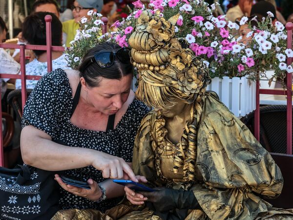 امرأة ترتدي ثوبًا ذهبيًا وتتحدث إلى صديقتها في وسط وارسو، بولندا. - سبوتنيك عربي