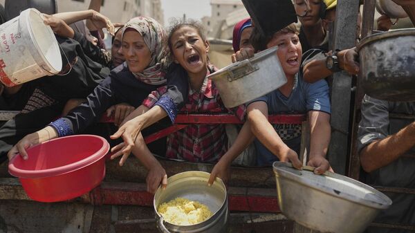 يكافح الفلسطينيون للحصول على الطعام المتبرع به في مطبخ مجتمعي في مدينة غزة، شمال قطاع غزة، 16 أغسطس/آب 2025 - سبوتنيك عربي