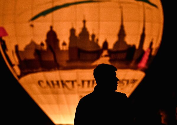 يشاهد أحد الزوار عرضًا ضوئيًا تضيء فيه المناطيد في سماء المساء في مهرجان &quot;احلم! حلق!&quot; في الذكرى السنوية الـ300 لتأسيس حديقة سانت بطرسبرغ. - سبوتنيك عربي