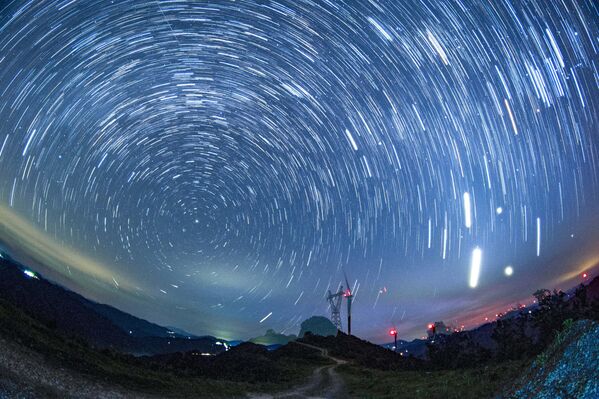 صورة بتقنية التصوير الفاصل الزمني تُظهر حركة النجوم فوق مزرعة الرياح في جبل دابانغ في ليلة صافية في الصين. - سبوتنيك عربي