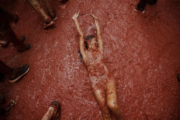 امرأة تتفاعل مع المشاركين في مهرجان الطماطم السنوي "توماتينا"، الذي يتبادلون فيه رشق بعضهم بالطماطم، في قرية بونول بالقرب من فالنسيا في إسبانيا. - سبوتنيك عربي