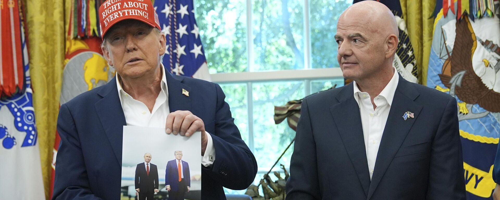 الرئيس الأمريكي دونالد ترامب يحمل صورة له مع الرئيس الروسي فلاديمير بوتن بينما يشاهده رئيس الاتحاد الدولي لكرة القدم (فيفا) جياني إنفانتينو خلال إعلان في المكتب البيضاوي بالبيت الأبيض. - سبوتنيك عربي, 1920, 03.04.2026