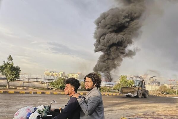 أشخاص يركبون دراجة نارية بينما يتصاعد الدخان في أعقاب الغارات الجوية الإسرائيلية على مناطق متعددة بما في ذلك محطة طاقة ومحطة وقود في صنعاء في اليمن. - سبوتنيك عربي