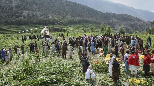 يتجمع السكان المحليون حول مروحية عسكرية هبطت لإجلاء الضحايا المصابين في زلزال أودى بحياة العديد من الأشخاص ودمر قرى في شرق أفغانستان، في مزار دارا، ولاية كونار، أفغانستان، يوم الاثنين 1 سبتمبر/أيلول 2025. - سبوتنيك عربي