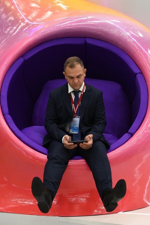 صورة لأحد المشاركين في المنتدى وهو يجلس ويتصفح  هاتفه الخلوي.  - سبوتنيك عربي