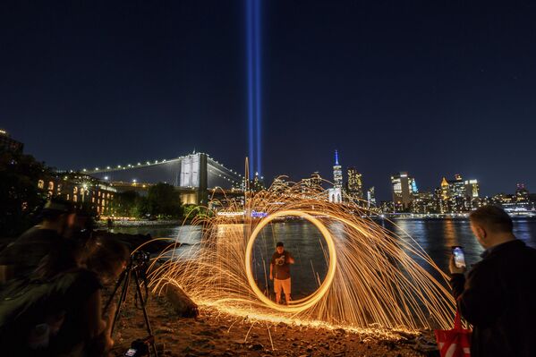 شخص يغزل صوفًا فولاذيًا بينما يضيء التكريم السنوي بالضوء في السماء خلف جسر بروكلين،  في نيويورك.  - سبوتنيك عربي