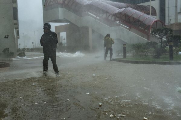 أشخاص يسيرون عبر مياه الفيضانات في منطقة هنغ فا تشوين، مع اقتراب الإعصار "راغاسا" في هونغ كونغ. - سبوتنيك عربي