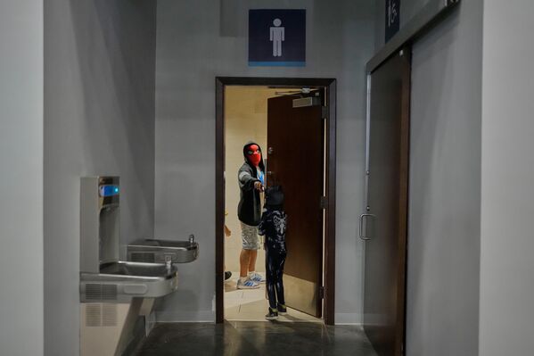 رجل يرتدي قناع سبايدرمان ويتحدث إلى ابنه أثناء خروجه من الحمام خلال مؤتمر كوميك كون في مدينة بنما. - سبوتنيك عربي