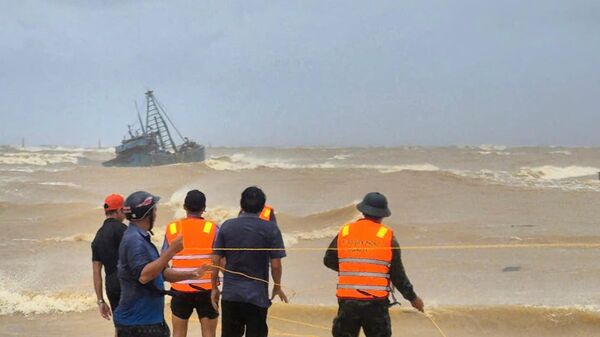 Люди спасают рыбаков с застрявшей на мели рыболовной лодки из-за тайфуна Буалой в Куангчи, Вьетнам - سبوتنيك عربي