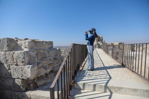 سائحة تقف على جسر، وتلتقط صورة فوتوغرافية لقلعة حلب. - سبوتنيك عربي