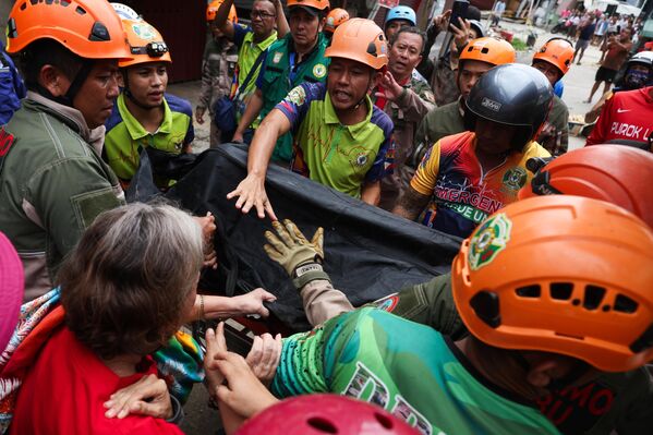 رجال الإنقاذ ينقلون جثمان أحد المتوفين نتيجة الزلزال في مدينة بوغو، الفلبين. - سبوتنيك عربي