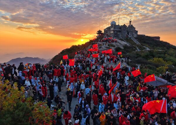 مواطنون يحملون أعلامًا وطنية صينية على جبل تايآن، احتفالًا بالذكرى السادسة والسبعين لتأسيس جمهورية الصين الشعبية في مقاطعة شاندونغ الصينية. - سبوتنيك عربي