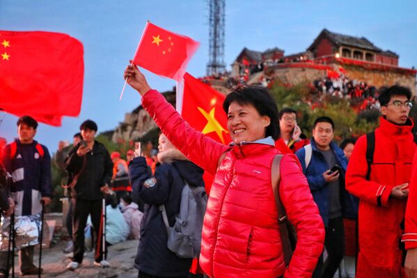 مواطنون يحملون أعلامًا وطنية صينية على جبل تايآن، احتفالًا بالذكرى السادسة والسبعين لتأسيس جمهورية الصين الشعبية. - سبوتنيك عربي