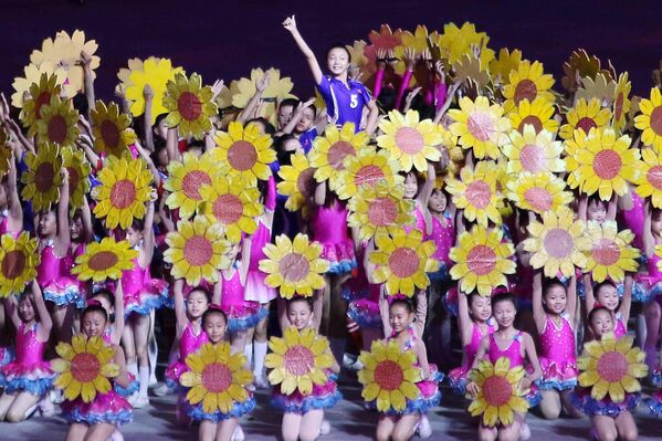 إحدى الفرق المشاركة في العرض حيث أدت الفيتات رقصات مميزة خلال حملهن الزهور بمشاركة شبان في ملعب ماي داي. - سبوتنيك عربي