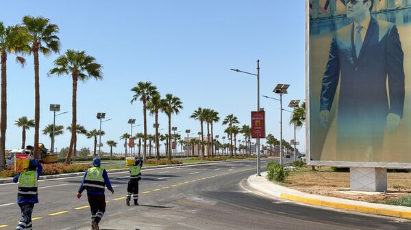 عمال يحملون طلاءً أثناء مرورهم أمام لافتة تحمل صورة الرئيس المصري عبد الفتاح السيسي في مدينة شرم الشيخ، حيث يعقد الرئيس دونالد ترامب قمة لزعماء العالم بشأن غزة خلال زيارته - سبوتنيك عربي
