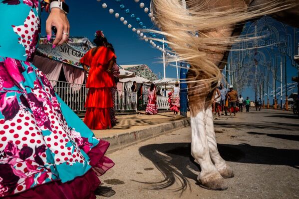تصوير الشارع - دوامتان.  معرض لا لينيا هو معرض صغير ساحر يقام في أقصى جنوب الأندلس، حيث يلتقي دفء الشمس بروح التقاليد النابضة بالحياة. تلعب الخيول، بحركاتها الرشيقة، وفساتين الفلامنكو الزاهية والملونة، دورا محوريا، فتملأ الأجواء بطاقة لا تقاوم وشعورا لا يضاهى بالحيوية. تمتزج هذه العناصر الأيقونية لتقدم عرضا آسرا للثقافة الأندلسية. لا لينيا دي لا كونسيبسيون، الأندلس (إسبانيا) - جيدو فان دير زوان - سبوتنيك عربي