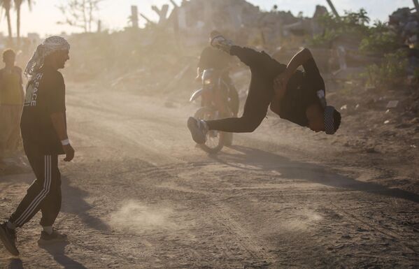 رياضيون فلسطينيون شباب يؤدون حركات باركور بين أنقاض المباني المدمرة في منطقة المغراقة، عقب وقف إطلاق النار في مدينة غزة.يستخدم الرياضيون رياضتهم للفت الانتباه إلى الدمار الذي خلفته الهجمات الإسرائيلية، مستعرضين مهاراتهم البهلوانية وسط الأنقاض. - سبوتنيك عربي