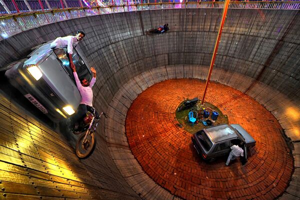  الممثلان المغامران بابار خان، وأجيم خان، يؤديان عرضًا بدراجة وسيارة في &quot;بئر الموت&quot;، المعروف محليًا باسم &quot;ماوت كا كوان&quot; في أرض معرض &quot;ميلا&quot; - سبوتنيك عربي