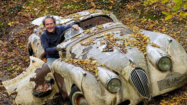 جامع السيارات مايكل فروليش أمام سيارة جاكوار كلاسيكية في حديقته الخاصة في ميتمان، ألمانيا. - سبوتنيك عربي