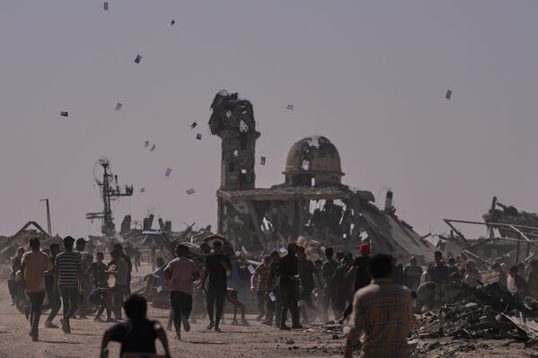 فلسطينيون يجمعون منشورات ألقتها طائرة إسرائيلية دون طيار تحذر الناس من الاقتراب من الخط الأصفر في خان يونس، جنوبي قطاع غزة. - سبوتنيك عربي