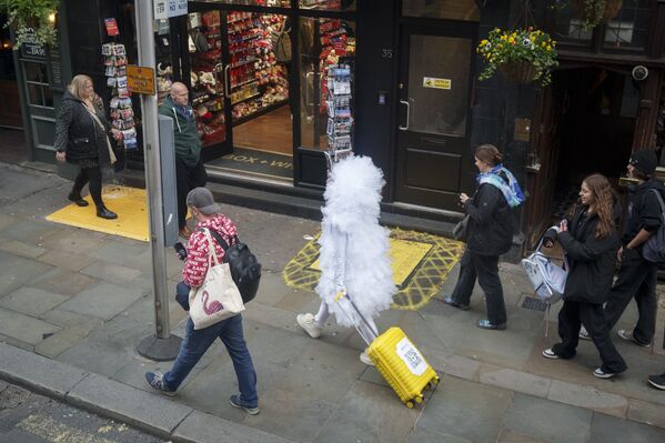 شخص يرتدي زيًا أبيض رقيقًا يسحب حقيبة سفر صفراء في وايت هول، في 22 أكتوبر 2025، لندن، إنجلترا. - سبوتنيك عربي