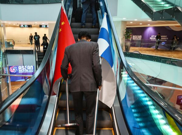 شخص يحمل الأعلام ويصعد على السلم الكهربائي في مركز كوالالمبور للمؤتمرات والمعارض، حيث تقام القمة الـ47 لرابطة دول جنوب شرق آسيا في ماليزيا - سبوتنيك عربي