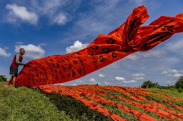 عامل إندونيسي يلقي قماشًا ملونًا بنقش الباتيك على ضفة نهر في سوكوهارجو، جاوة الوسطى، إندونيسيا، في 27 أكتوبر/تشرين الأول 2025. - سبوتنيك عربي