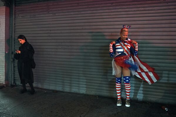 أحد الأشخاص يرتدي زيًا غريبًا بألوان العلم الأمريكي، ينتظر وصول موكب "الهالوين" في نيويورك. - سبوتنيك عربي