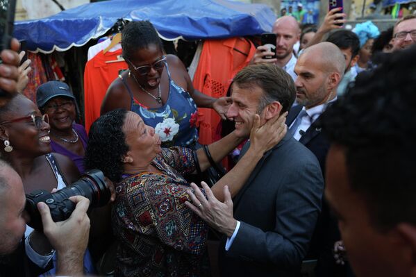 الرئيس الفرنسي إيمانويل ماكرون يحيي امرأة خلال زيارته إلى حي بيلورينهو في سالفادور، ولاية باهيا، البرازيل. - سبوتنيك عربي