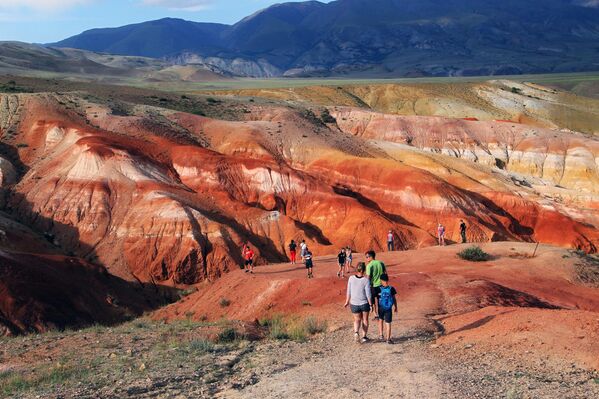 سياح في وادي كيزيل تشين في سهوب تشويا بجمهورية ألتاي. يُضفي ارتفاع نسبة الزئبق في الصخور لونًا أحمر. سياح في وادي كيزيل تشين في سهوب تشويا بجمهورية ألتاي. يُضفي ارتفاع نسبة الزئبق في الصخور لونًا أحمر. - سبوتنيك عربي