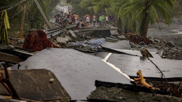 Жители осматривают шоссе, разрушенное во время супертайфуна Фунг-вонг в Дипакулао, провинция Аврора, Филиппины - سبوتنيك عربي