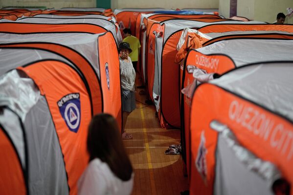 امرأة تمشي بجانب الخيم في مراكز الإجلاء، تزامنا مع دخول إعصار فونغ وونغ البلاد. - سبوتنيك عربي