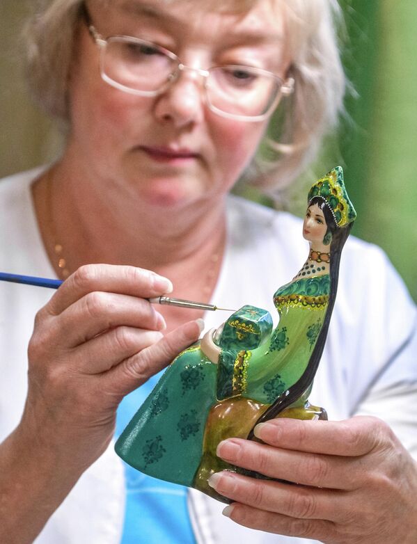 امرأة مسنة، تقوم بوضع نقوشات على منتج مصنوع من الخزف. - سبوتنيك عربي