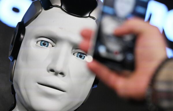  صورة قريبة لوجه الروبوت &quot;أيدول&quot;، حيث تظهر يد بشرية تقوم بالتقاط صورة له. - سبوتنيك عربي