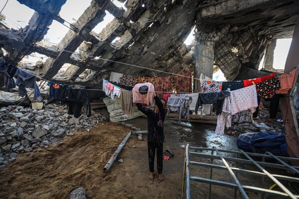 صورة توثق معاناة الفلسطينيين وسط أنقاض المباني، التي دمرتها الحرب الإسرائيلية على قطاع غزة، في أعقاب وقف إطلاق النار وانسحاب القوات الإسرائيلية من حي &quot;الشجاعية&quot;، شرقي مدينة غزة - سبوتنيك عربي