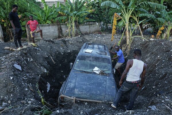 سكان يعملون على إزالة مركبة مدفونة جزئيًا في أعقاب إعصار &quot;ميليسا&quot; في هايتي - سبوتنيك عربي