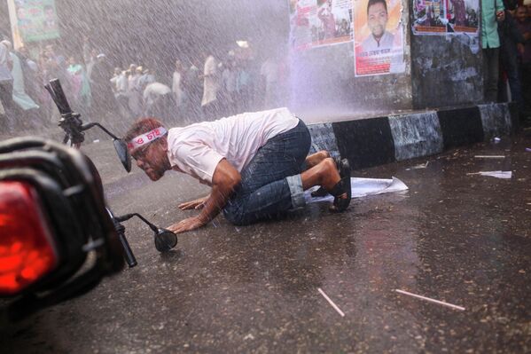 اختباء أحد المتظاهرين، خلال قيام الشرطة البنغلاديشية، باستخدام قنابل الصوت ومدافع المياه والهراوات لتفريق المعلمين، أثناء توجههم نحو الأمانة العامة للمطالبة بإدراجهم في نظام الأجور الشهرية في دكا  - سبوتنيك عربي