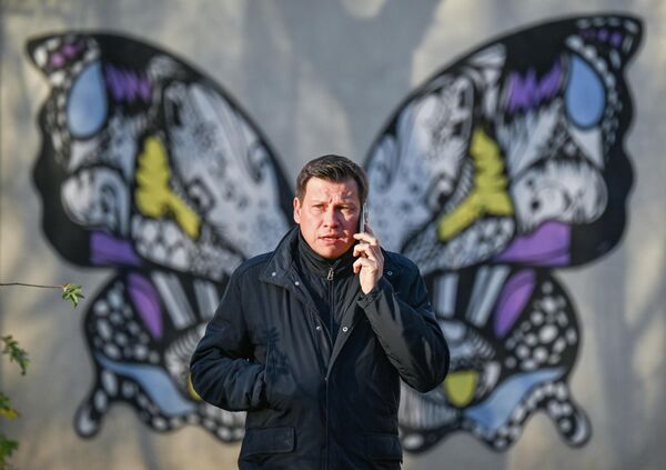 رجل يتحدث على الهاتف في حديقة في موسكو وكأن لديه جناحي فراشة - سبوتنيك عربي