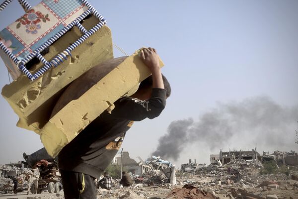 فلسطينيون يحملون البطانيات والملابس، التي جُمعت من أنقاض منازلهم، التي دُمرت جراء الهجمات الإسرائيلية - سبوتنيك عربي