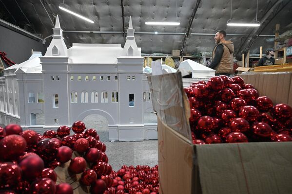 صورة تظهر صناديق تحتوي طابات حمراء لزينة  شجرة عيد الميلاد، ويظهر في الخلفية مجسم لأحد مباني موسكو. - سبوتنيك عربي