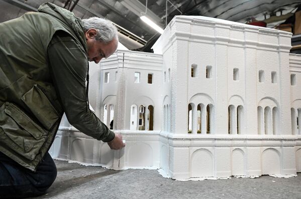 وضع الرتوش الأخيرة على مجسم أحد المباني المطلية باللون الأبيض، والذي ستزيّن به شجرة عيد الميلاد. - سبوتنيك عربي